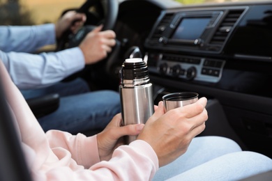 Photo of Woman with thermos on passenger seat of car, closeup