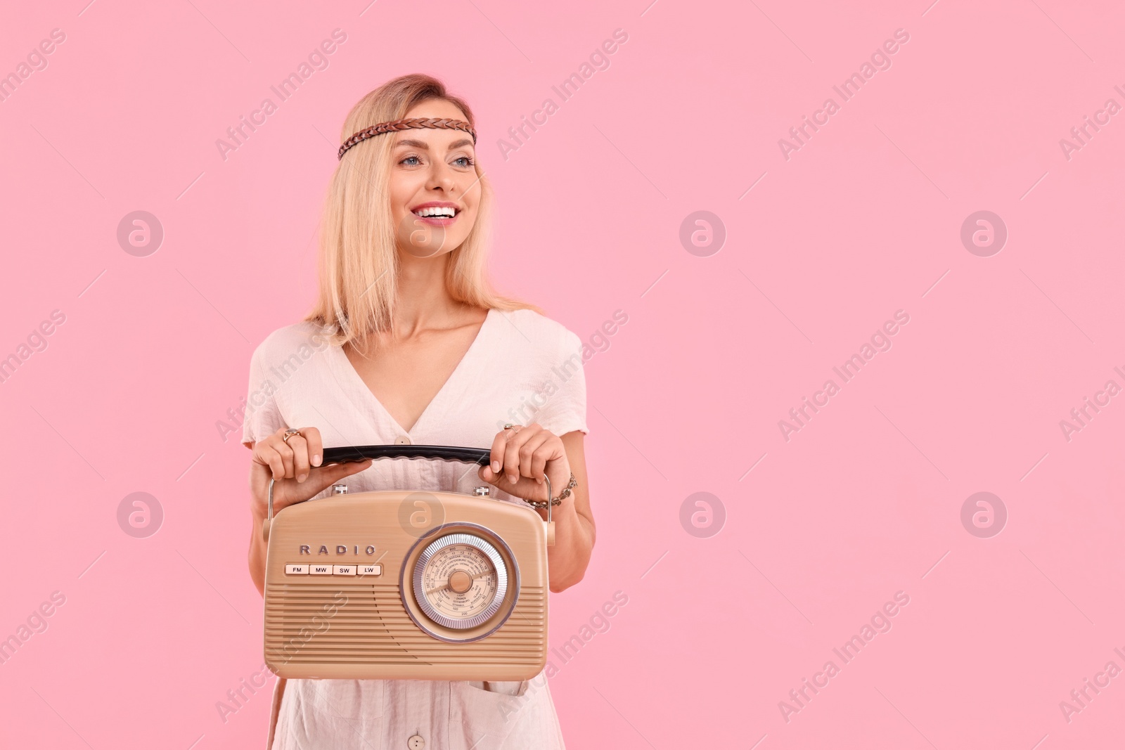 Photo of Portrait of happy hippie woman with retro radio receiver on pink background. Space for text