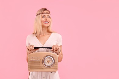 Portrait of happy hippie woman with retro radio receiver on pink background. Space for text