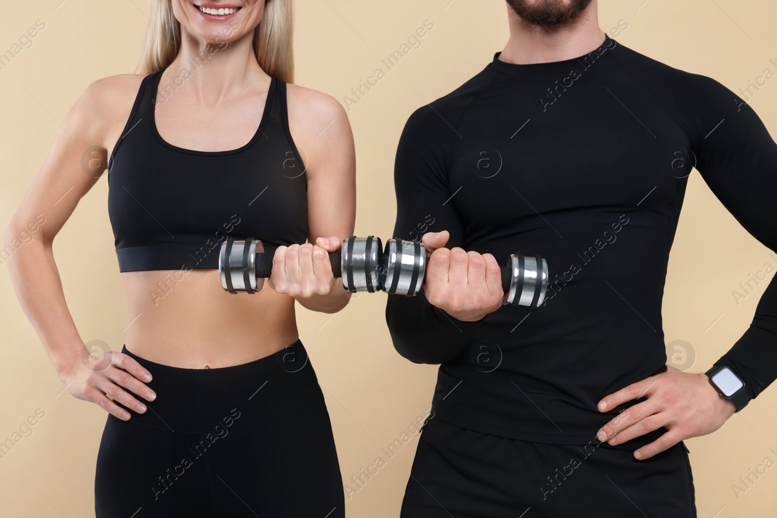 Photo of Athletic people exercising with dumbbells on light brown background, closeup