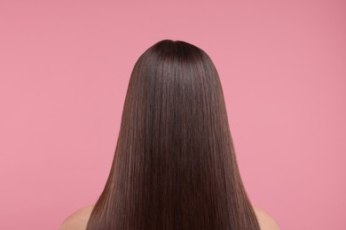 Woman with smooth healthy hair after treatment on pink background, back view