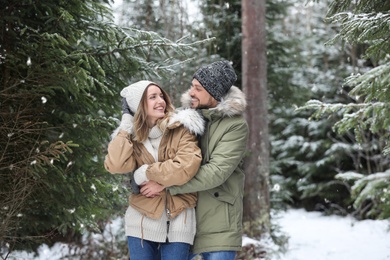 Photo of Couple in conifer forest on snowy day. Winter vacation