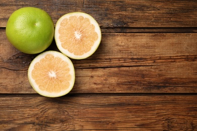 Whole and cut sweetie fruits on wooden table, flat lay. Space for text