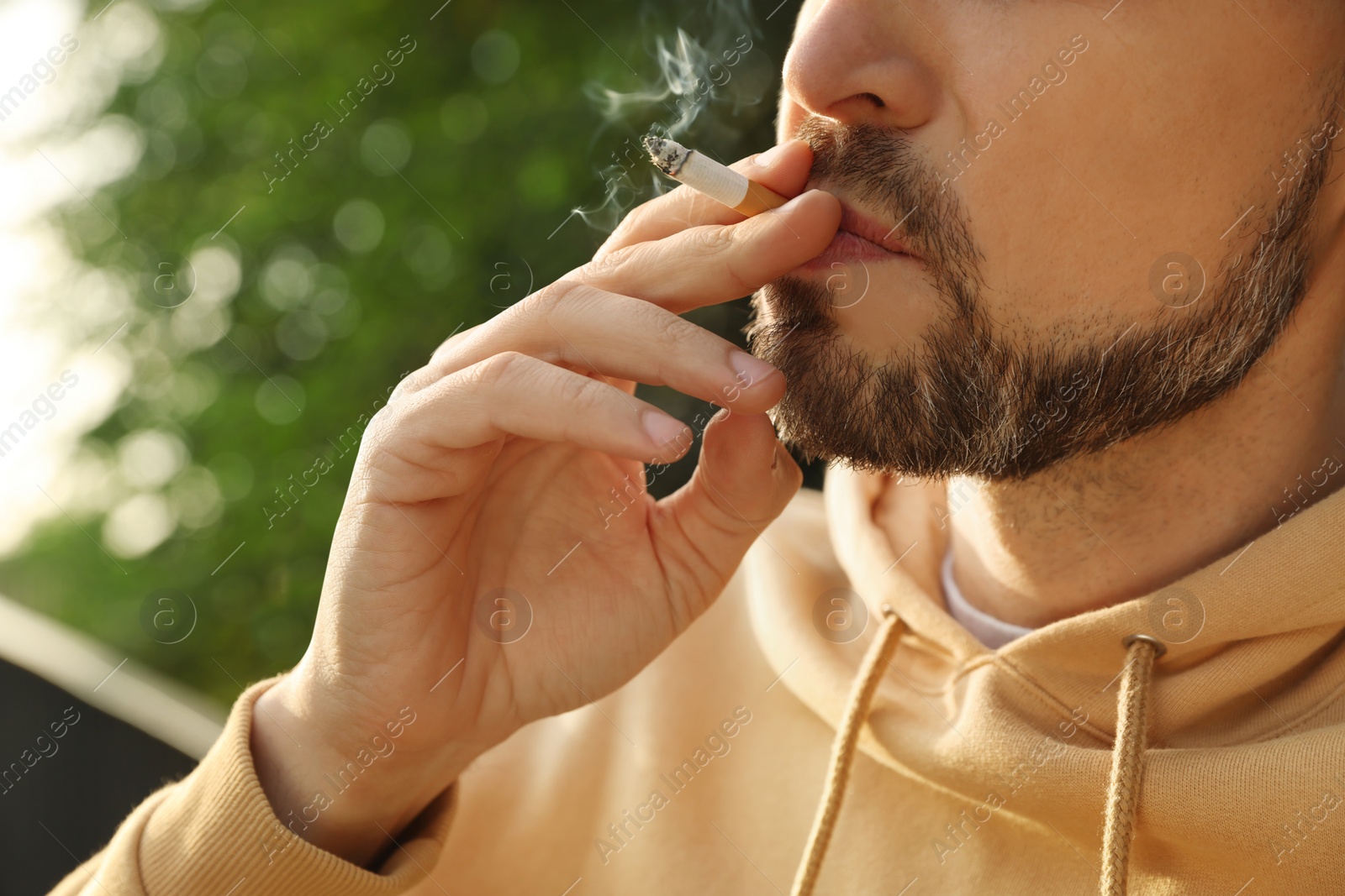 Photo of Handsome mature man smoking cigarette outdoors, closeup