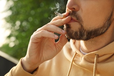 Handsome mature man smoking cigarette outdoors, closeup
