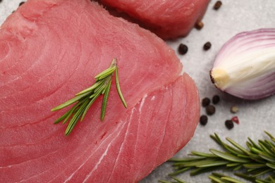 Photo of Fresh raw tuna fillet with rosemary on light gray table, top view