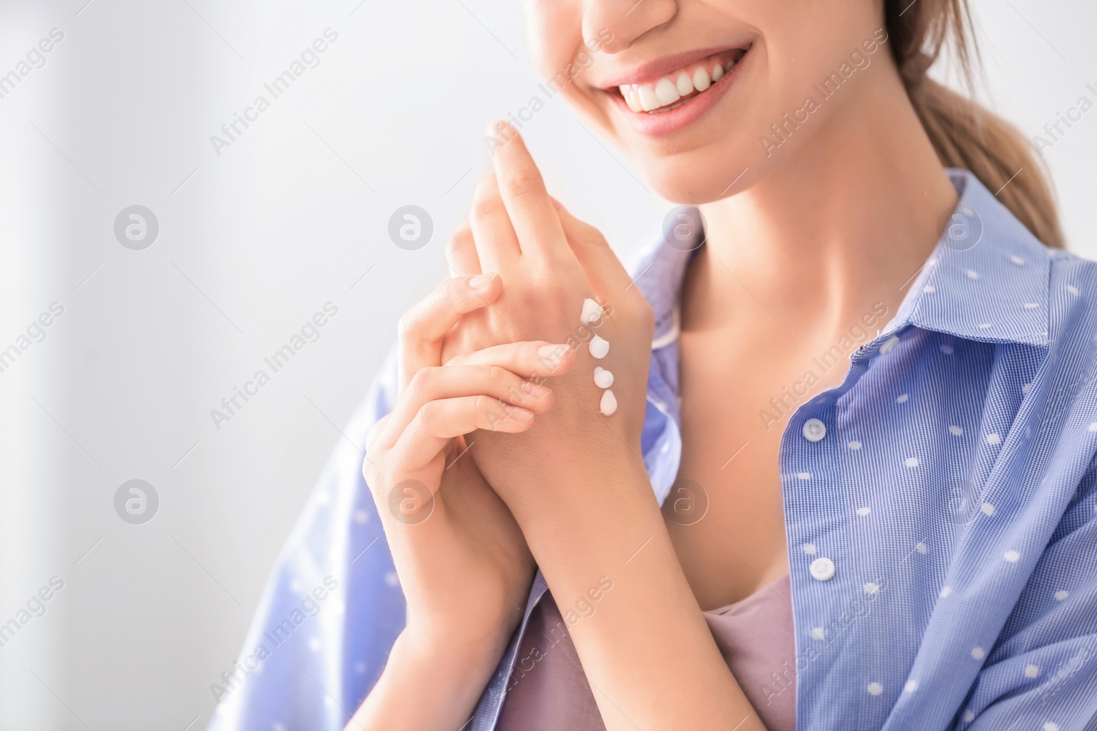 Photo of Young woman applying hand cream at home, closeup