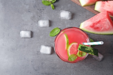 Glass of tasty refreshing drink with watermelon on grey table, top view. Space for text