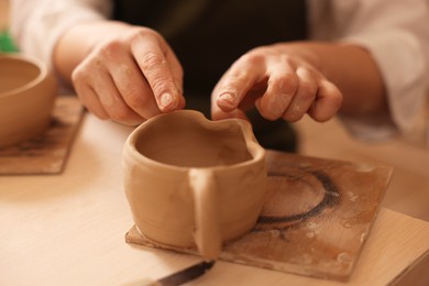 Photo of Pottery crafting. Woman sculpting with clay at table, closeup