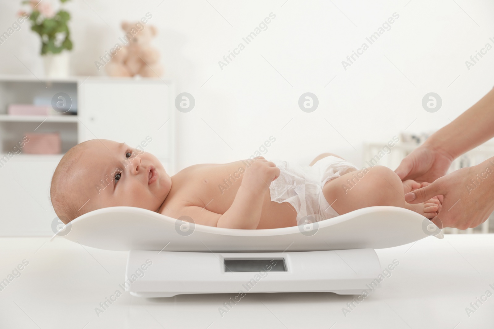 Photo of Doctor weighting baby on scales in light room