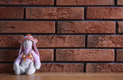 Photo of Abandoned toy bunny on table against brick wall background. Time to visit child psychologist