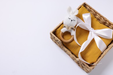 Baby accessory. Rattle and child`s clothes in wicker box on white background, top view. Space for text