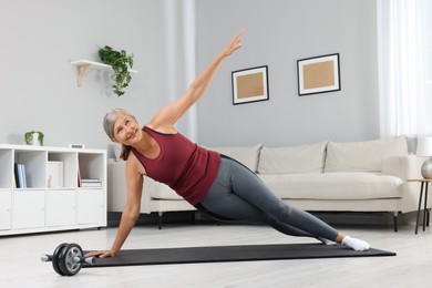 Senior woman in sportswear doing exercises on fitness mat at home