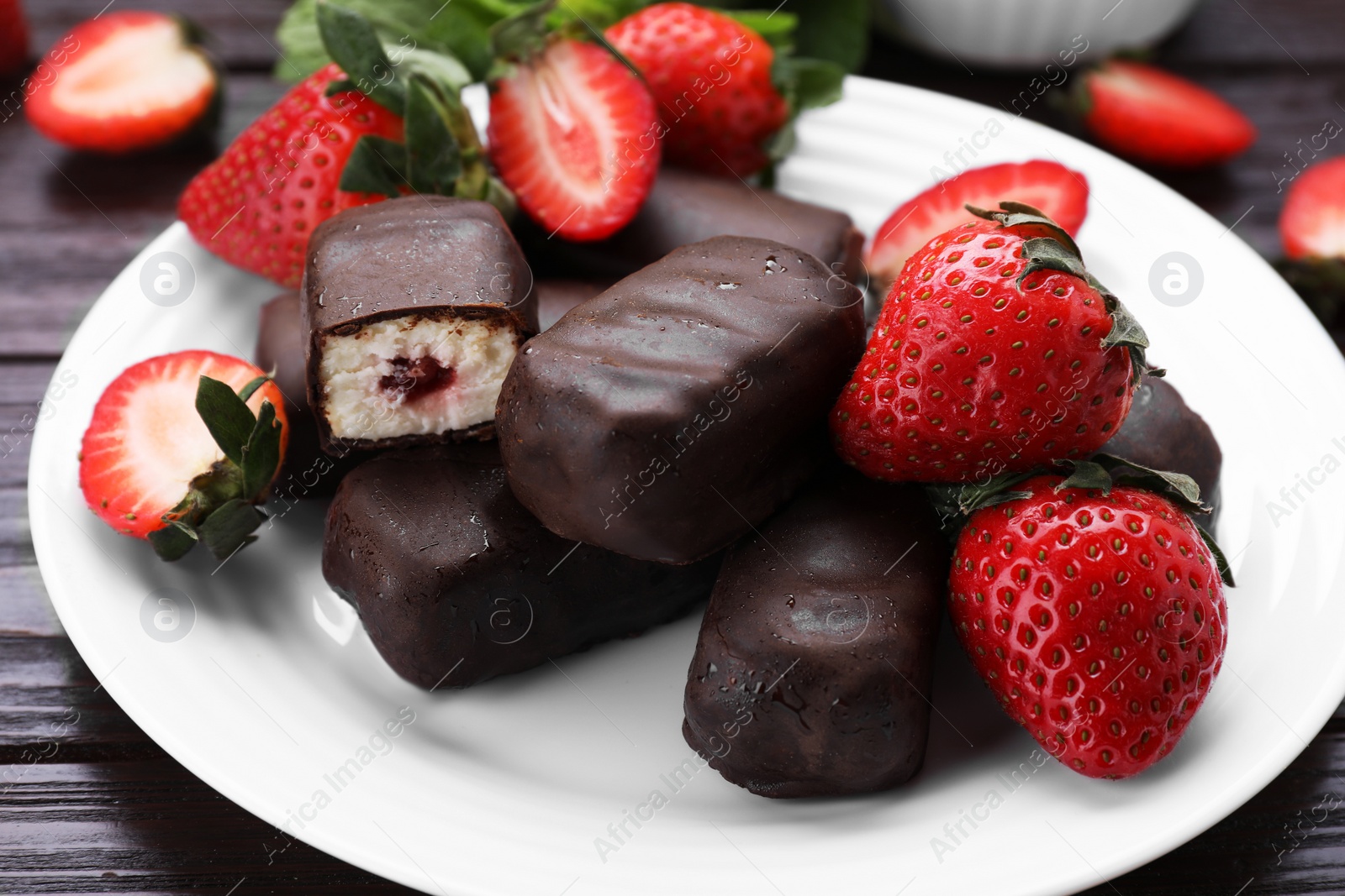 Photo of Delicious glazed curd snacks, mint leaves and fresh strawberries on wooden table, closeup