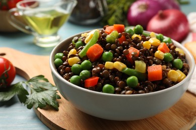Delicious lentils with vegetables on light blue table, closeup