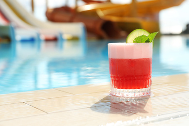 Photo of Glass of delicious cocktail near swimming pool, space for text. Refreshing drink