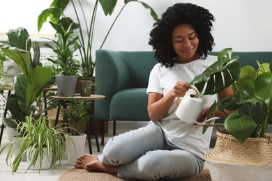 Photo of Happy woman watering beautiful monstera with water at home. Houseplant care