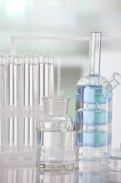 Laboratory analysis. Different glassware with liquid on white table against blurred background