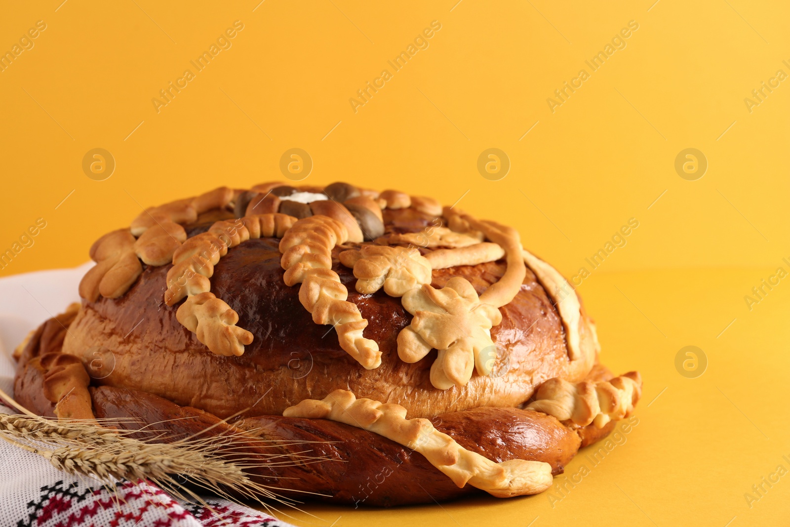 Photo of Rushnyk with korovai on yellow background. Ukrainian bread and salt welcoming tradition