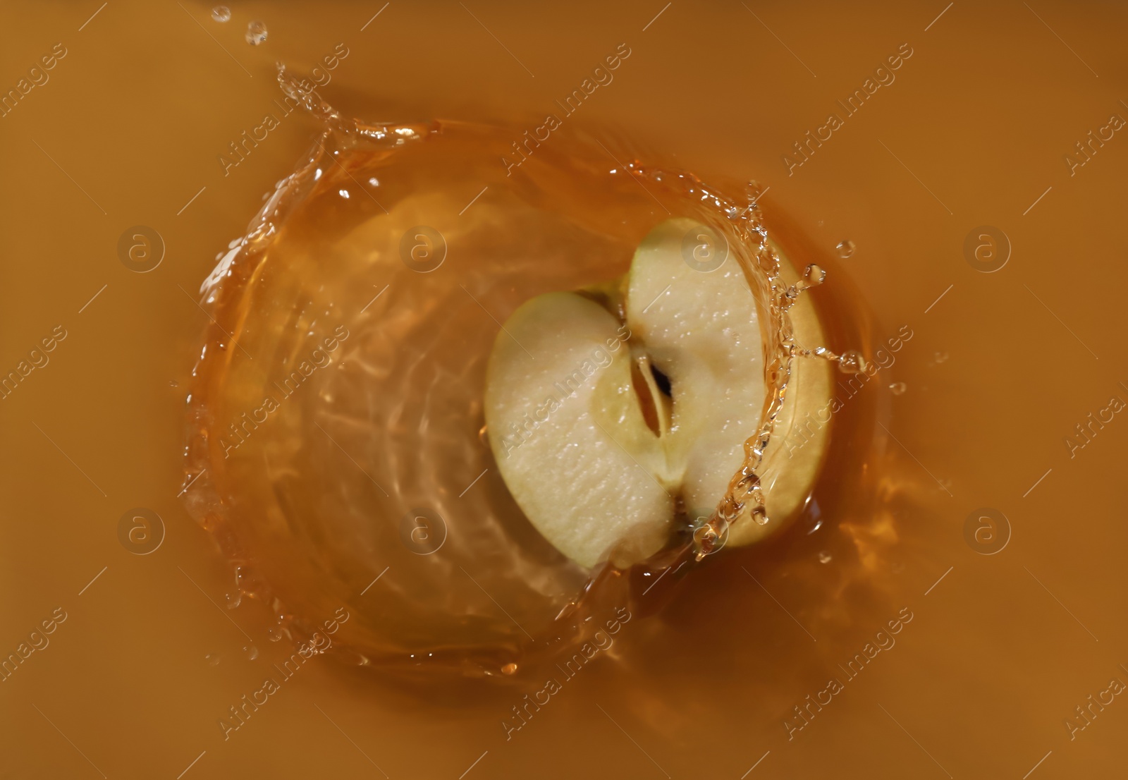 Photo of Half of apple falling in juice with splash, top view