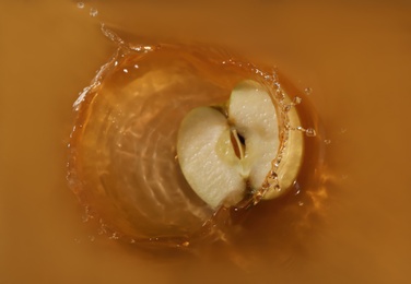 Half of apple falling in juice with splash, top view