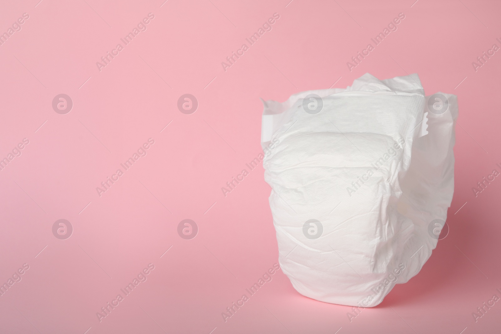 Photo of Baby diaper on pink background. Space for text