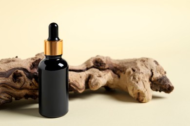 Photo of Bottle with cosmetic oil and wooden snag on beige background, closeup. Space for text