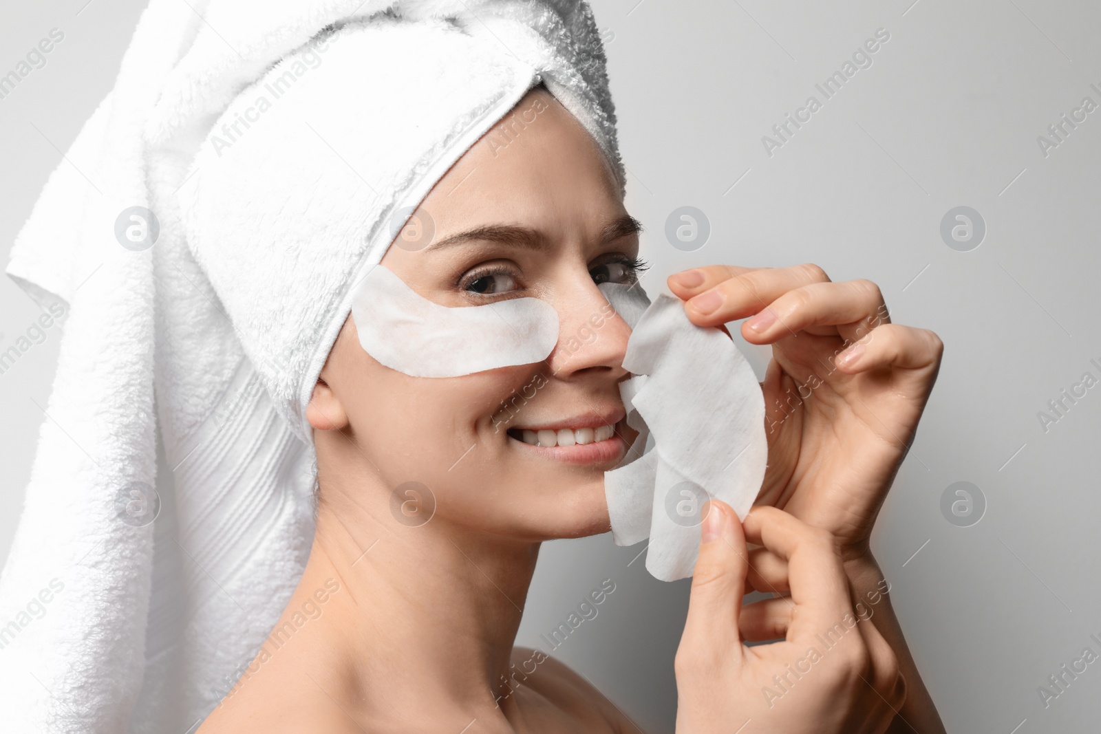 Photo of Beautiful woman with cotton face and eye masks against light background