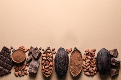 Photo of Flat lay composition with cocoa pods and chocolate on beige background, space for text