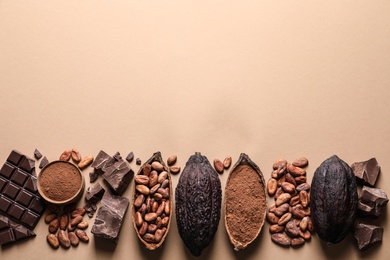 Flat lay composition with cocoa pods and chocolate on beige background, space for text