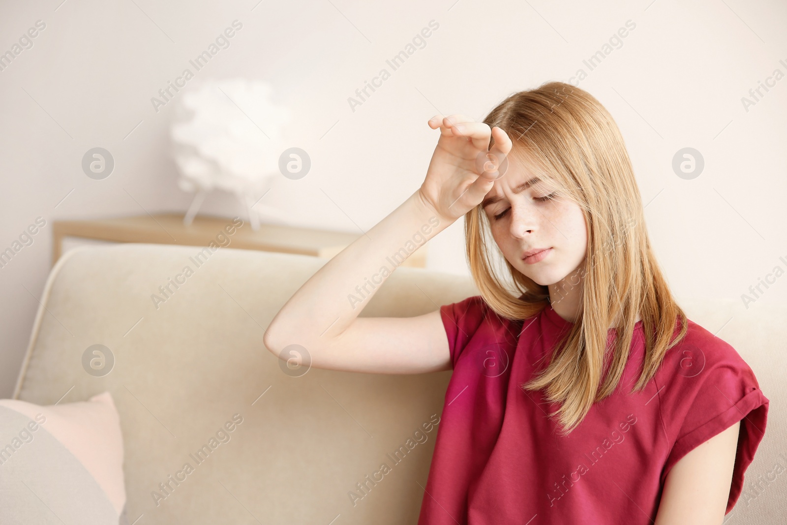 Photo of Teenage girl suffering from headache in living room