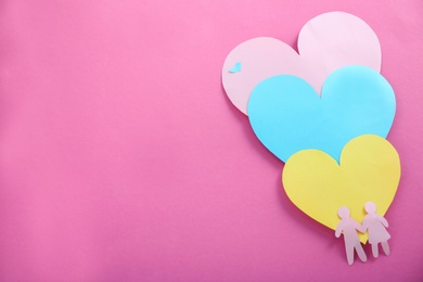 Photo of Paper silhouettes of people and hearts on color background, top view