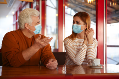 Photo of People with medical masks in cafe. Virus protection