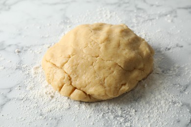 Photo of Making shortcrust pastry. Raw dough and flour on white marble table
