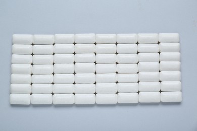 Tasty white chewing gums on light grey background, flat lay