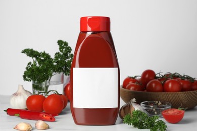 Bottle of tasty ketchup and ingredients on white marble table. Space for text