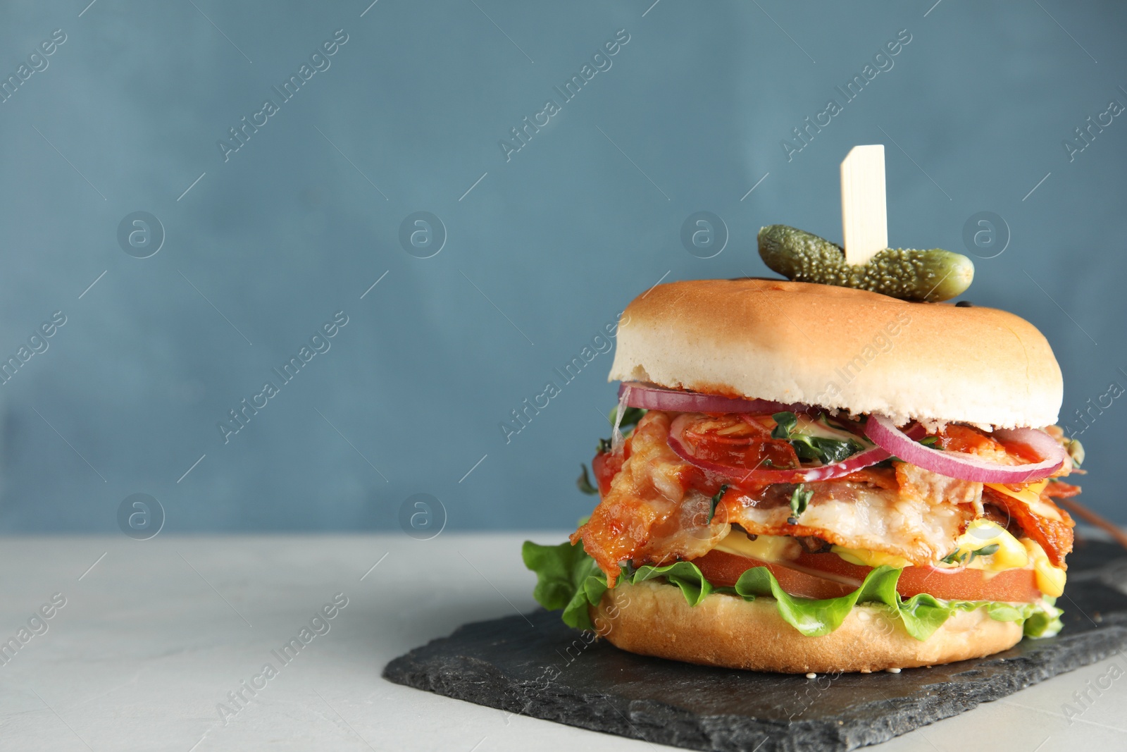 Photo of Tasty burger with bacon served on table. Space for text