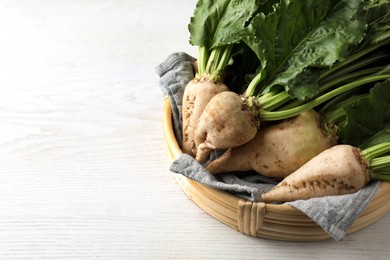 Photo of Basket with fresh sugar beets on white wooden table, above view. Space for text