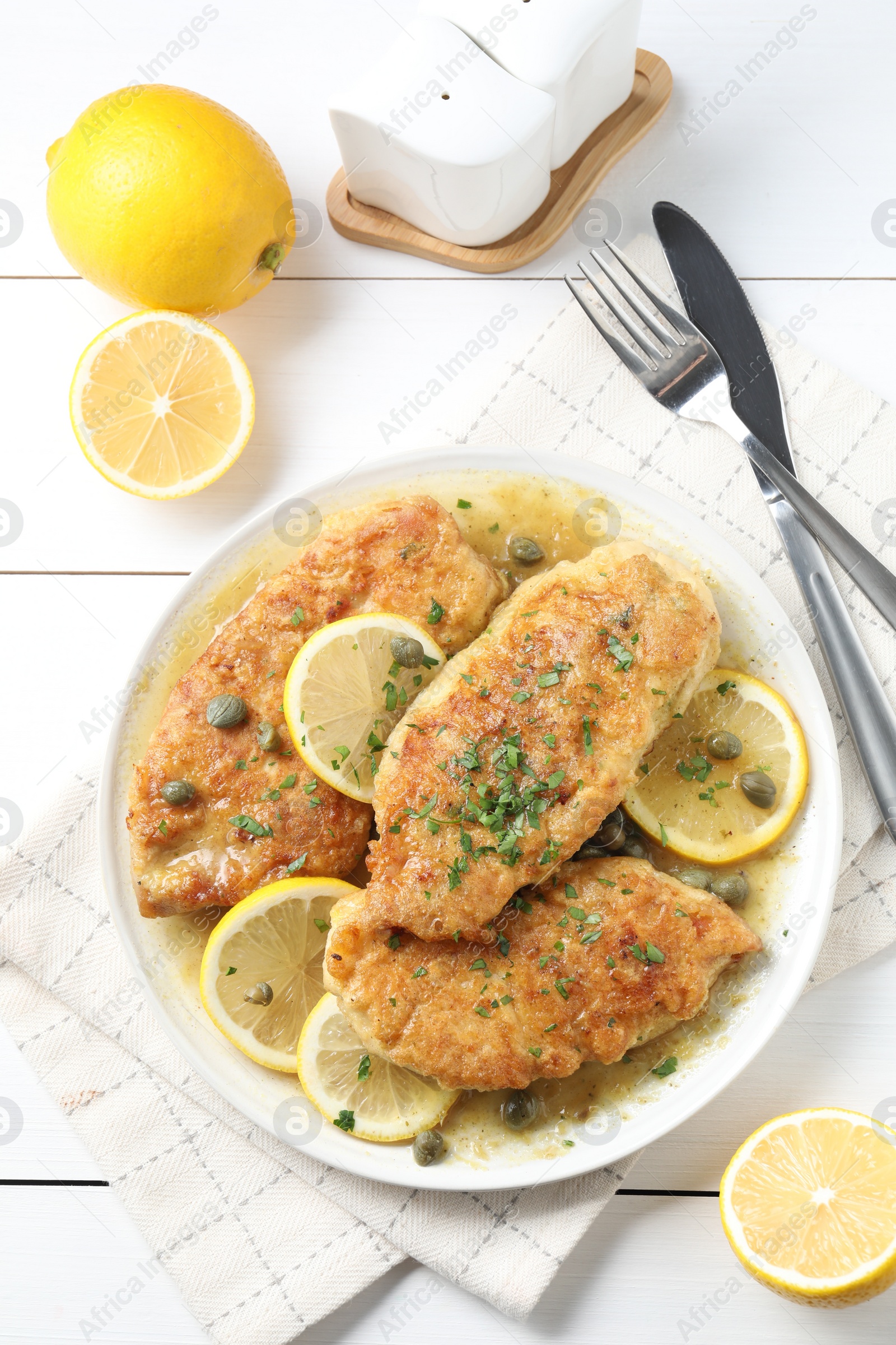 Photo of Delicious chicken piccata served on white table, flat lay