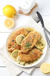 Delicious chicken piccata served on white table, flat lay