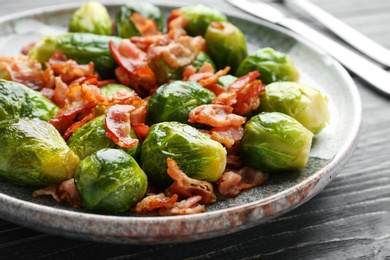 Tasty roasted Brussels sprouts with bacon on blue wooden table, closeup