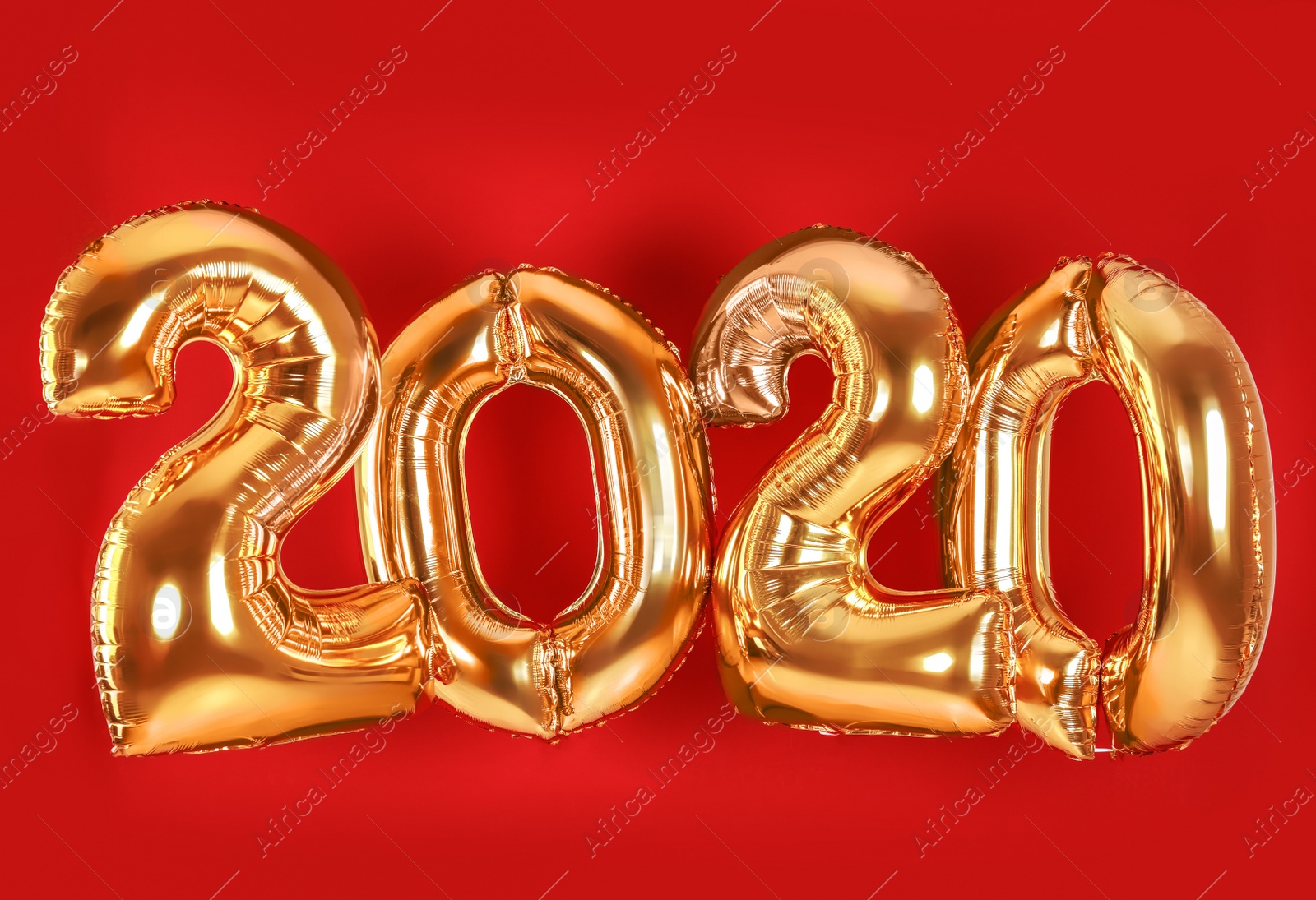 Photo of Golden balloons for party decoration on red background. 2020 New Year celebration