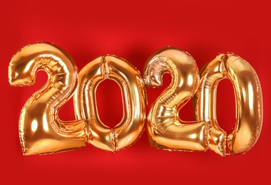 Golden balloons for party decoration on red background. 2020 New Year celebration