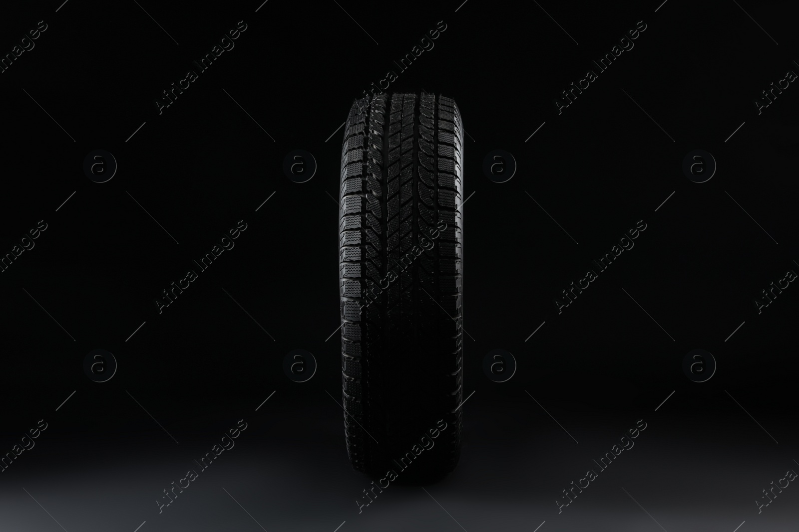 Photo of Winter tire on black background. Car maintenance