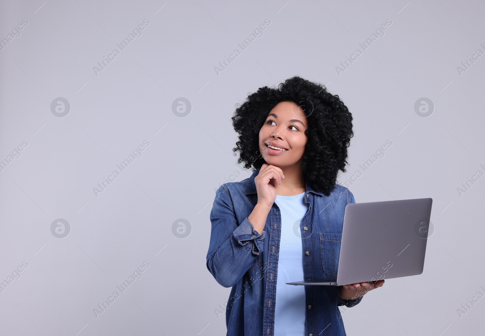 Photo of Happy young woman with laptop on light grey background. Space for text