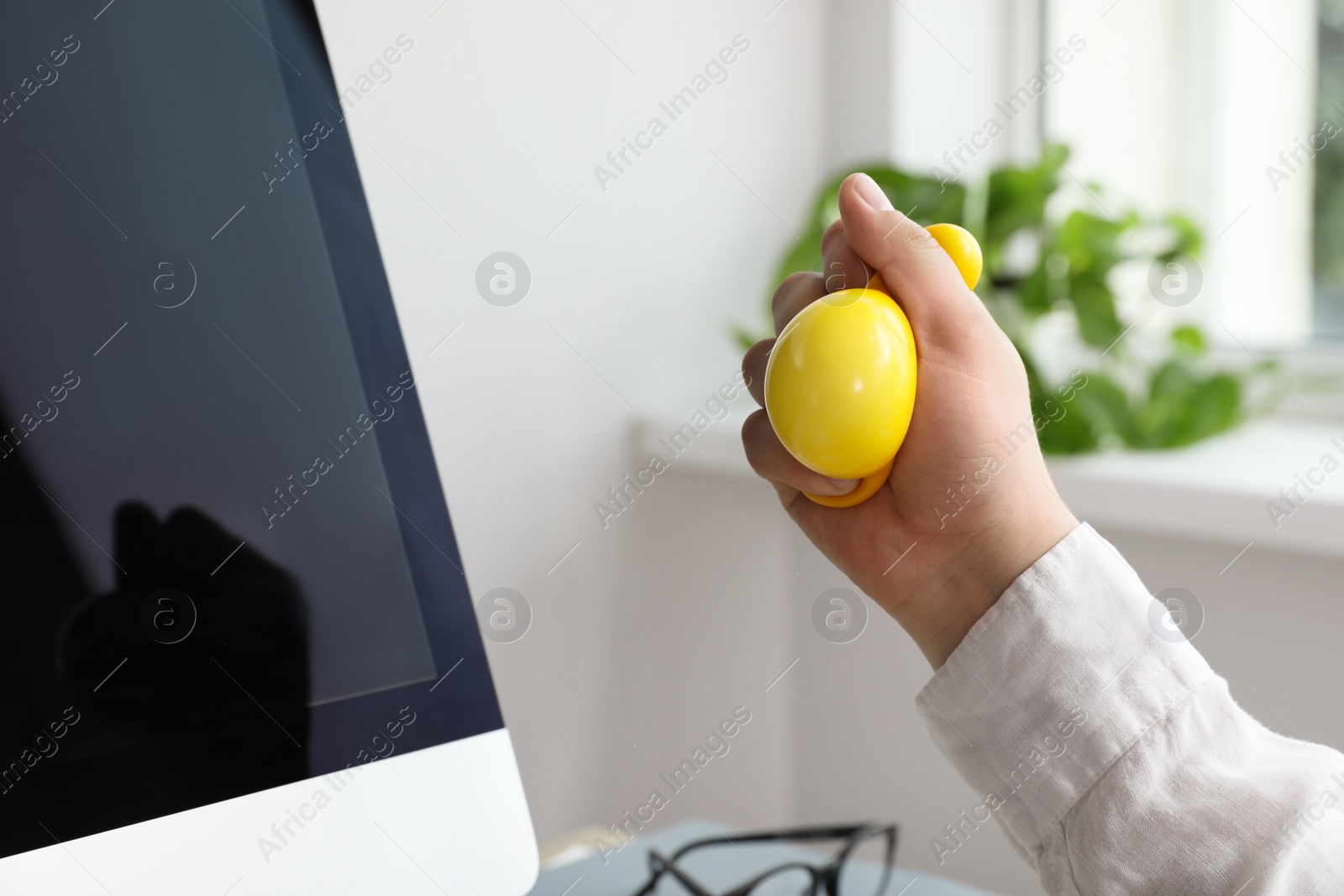 Photo of Man squeezing yellow stress ball in office, closeup