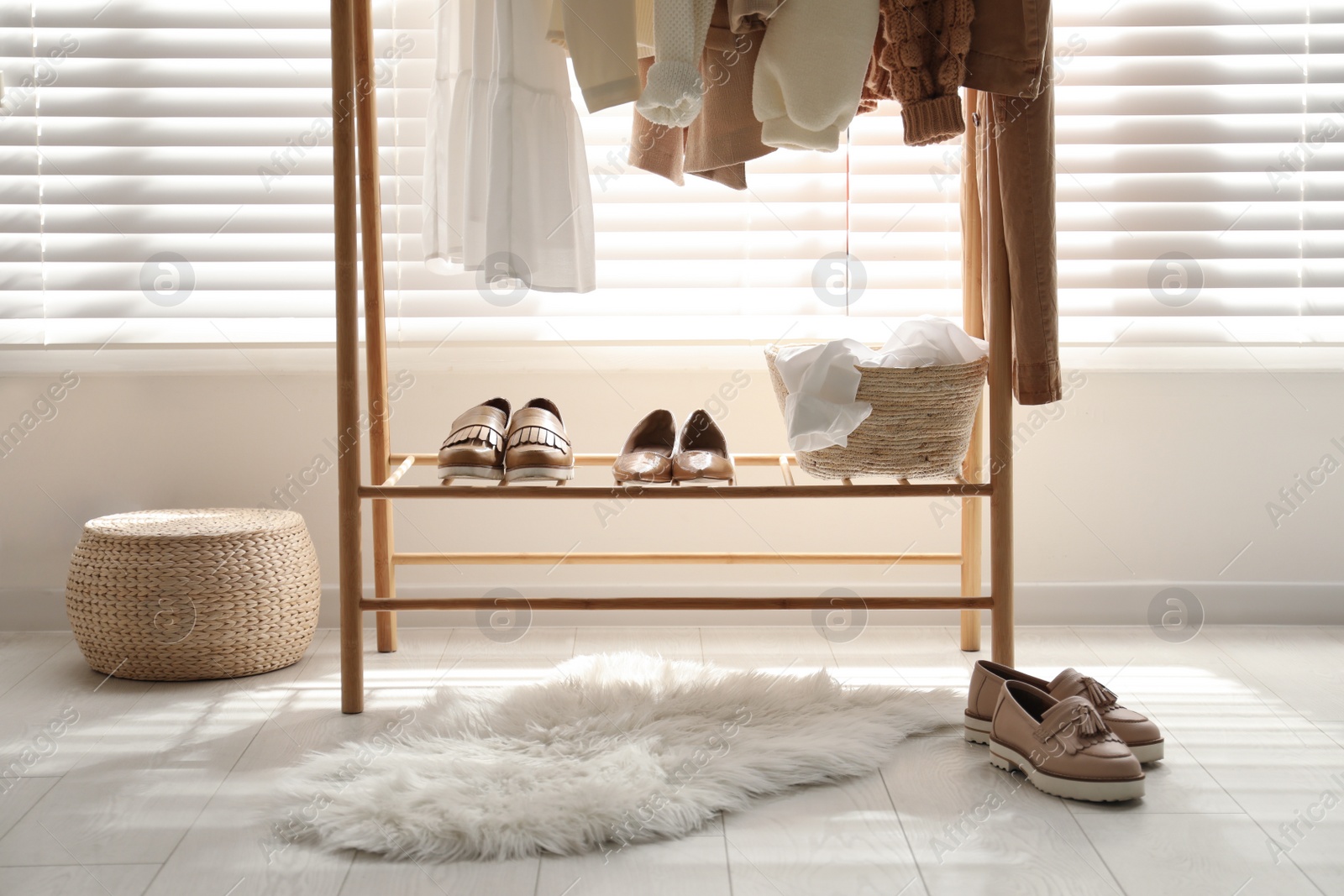 Photo of Rack with stylish shoes and women's clothes in dressing room. Modern interior design