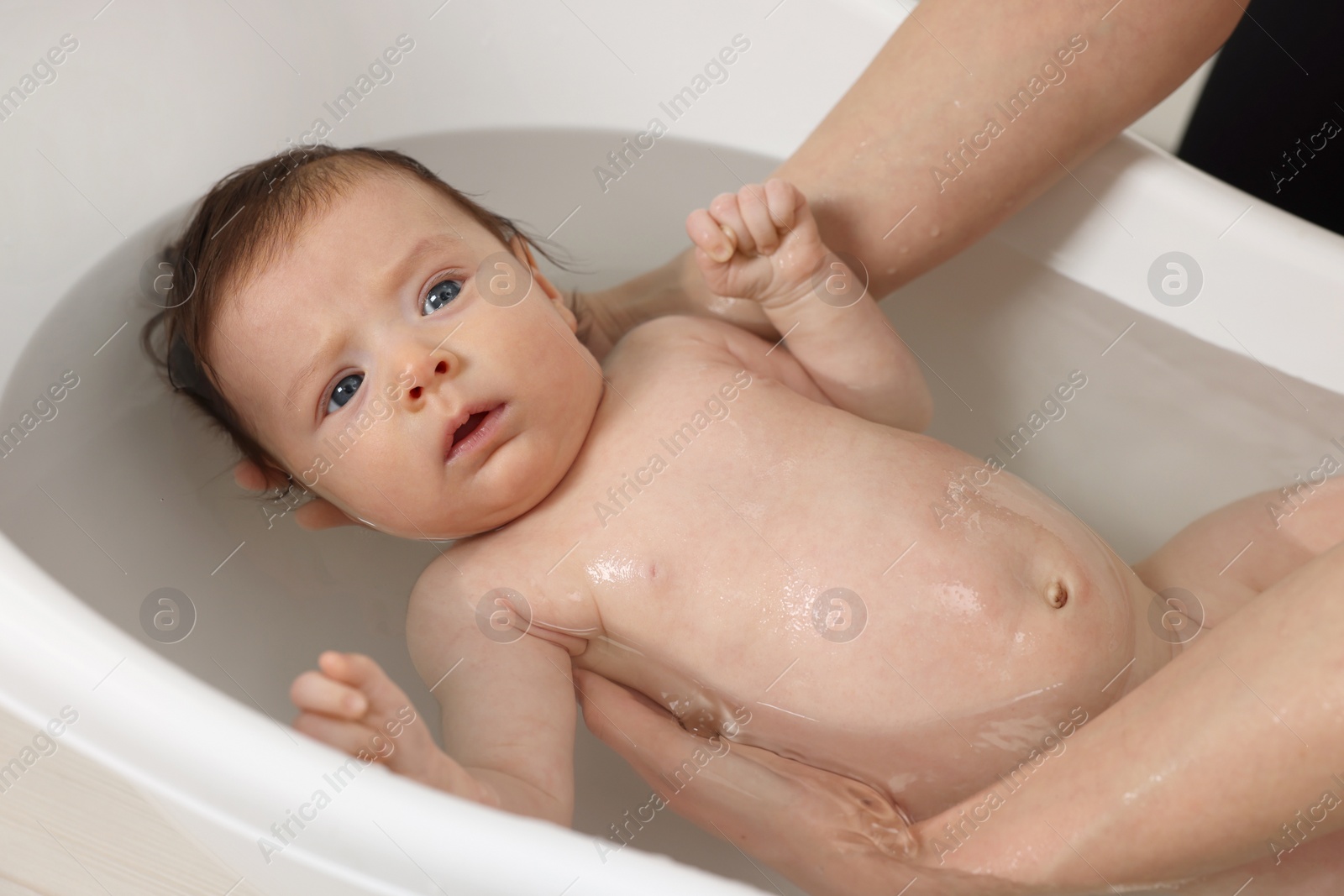 Photo of Mother bathing her little baby in bathtub, closeup