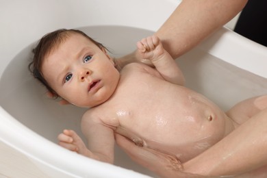 Mother bathing her little baby in bathtub, closeup