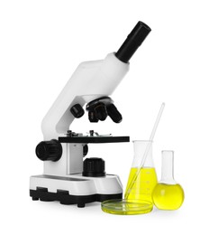 Photo of Laboratory glassware with yellow liquid and microscope isolated on white